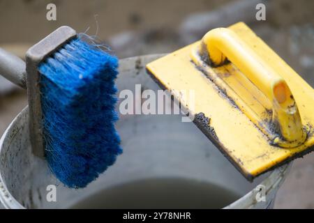 Spazzola e cazzuola per spatola su secchio in plastica da costruzione Foto Stock