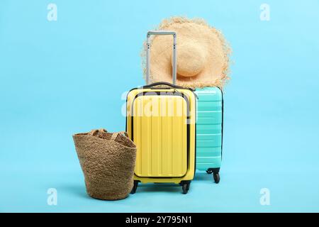 Valigie con cappello di paglia e borsa su sfondo azzurro Foto Stock