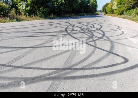 segni di slittamento sul fondo stradale. Segni circolari degli pneumatici lasciati dai conducenti che fanno le ciambelle. Foto Stock