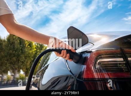 Stazione di ricarica per veicoli elettrici in città, che carica la sua auto elettrica. Energia pulita e consapevolezza ambientale. Foto Stock