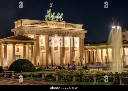 La porta di Brandeburgo illuminata di Berlino con una fontana di notte Foto Stock