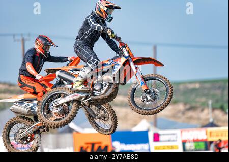 Agios Sozomenos, Cipro - 11 febbraio 2024: Due piloti di motocross che volano in aria sulle loro moto da terra durante una competizione campionaria Foto Stock