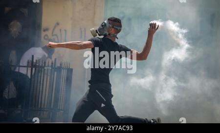 Un manifestante palestinese rilancia una granata di gas lacrimogeni contro le truppe israeliane durante una protesta contro il trasferimento dell'ambasciata americana a Gerusalemme e in vista del 70° anniversario di Nakba, al checkpoint di Qalandya vicino alla città di Ramallah, in Cisgiordania, il 14 maggio 2018. Secondo i rapporti dei media, almeno 41 palestinesi sono stati uccisi e più di 1800 feriti durante gli scontri al confine tra Gaza e Israele durante gli scontri contro il trasferimento dell'ambasciata americana a Gerusalemme, oltre a celebrare il Nakba Day. Foto Stock