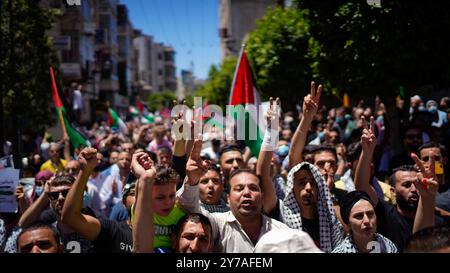 Cisgiordania, Palestina. 18 maggio 2021. I palestinesi marciano nella città di Ramallah in Cisgiordania gridando slogan contro l'occupazione di Israele e il suo continuo bombardamento della Striscia di Gaza. Proteste e feroci scontri sono scoppiati in molte parti della Cisgiordania in un "giorno di rabbia” palestinese martedì, durante il quale i palestinesi hanno osservato uno sciopero generale in Cisgiordania, Gerusalemme e città israeliane. Il confronto israelo-Gaza in corso è entrato in una seconda settimana con pesanti bombardamenti e razzi che hanno causato più vittime da entrambe le parti, specialmente nella densamente popolata Striscia di Gaza Foto Stock