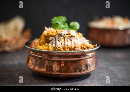 Pulao biryani indiano piccante in ciotola dorata con riso basmati indiano con curry di carne di pollo Ramadan Kareem, Eid. Recipiente da portata in ottone con dorso bianco Foto Stock