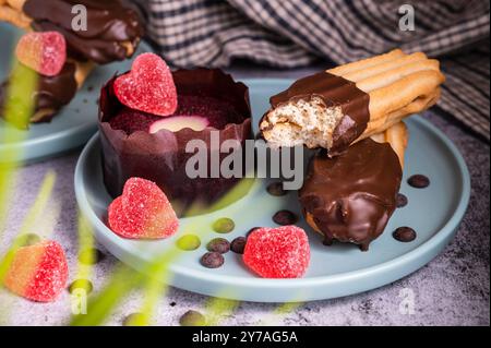 Cupcake di San Valentino. Biscotto digestivo rivestito di cioccolato fondente. Dolce delizioso tartufo da dessert e caramelle a forma di cuore su un piatto. Sfondo scuro wi Foto Stock