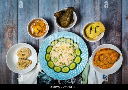 Decorazioni di piatti indiani assortiti su sfondo di legno scuro. Piatti e antipasti di cucina indiana. Fish Curry, pollo al burro, ciotole di riso e pla Foto Stock