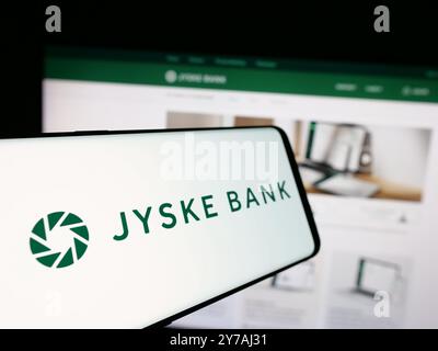 Telefono cellulare con logo della società finanziaria danese Jyske Bank sullo schermo di fronte al sito web aziendale. Mettere a fuoco la parte sinistra del display del telefono. Foto Stock