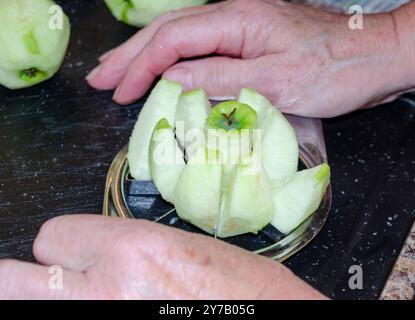 Mani di donna che usano un taglierino per mele per preparare le mele da cucinare Foto Stock