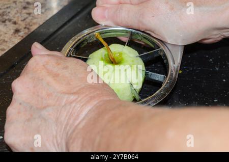 Le mani delle donne usano un taglierino per mele per preparare le mele per la cottura Foto Stock