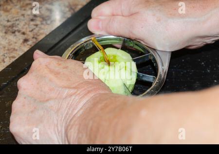 Mani di donna che usano un taglierino per mele per preparare le mele da cucinare Foto Stock