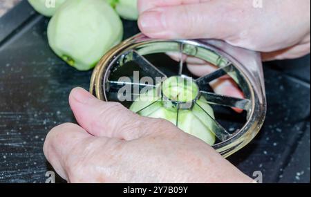 Le mani delle donne usano un taglierino per mele per preparare le mele per la cottura Foto Stock