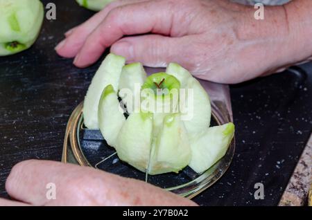 Le mani delle donne usano un taglierino per mele per preparare le mele per la cottura Foto Stock