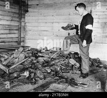 Un giovane membro della resistenza francese esamina stivali, scarpe e zoccoli di legno accumulati vicino a una fornace nel crematorio del campo di concentramento di Natzweiler-Struthof. Questo campo, in Alsazia, era l'unico campo nazista sul suolo francese. Era un campo di lavoro, un campo di transito e, con l'avanzare della guerra, un luogo di esecuzione. Si stima che 22.000 persone siano morte lì. Foto Stock