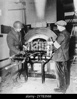 Un soldato americano e un membro della resistenza francese ispezionano il crematorio a Natzweiler-Struthof. Stanno tenendo un paio di pinze che sono state usate per maneggiare i corpi. Questo campo, in Alsazia, era l'unico campo nazista sul suolo francese. Era un campo di lavoro, un campo di transito e, con l'avanzare della guerra, un luogo di esecuzione. Si stima che 22.000 persone siano morte lì. Foto Stock