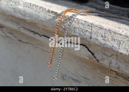 un paio di bracciali da tennis dorati su marmo Foto Stock