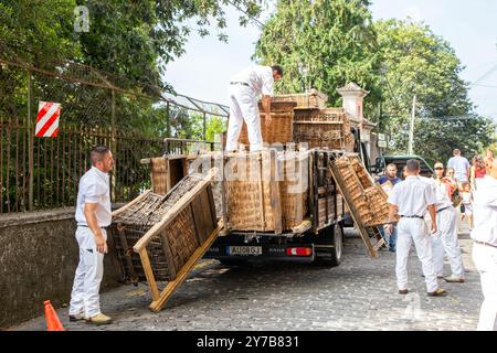 I corridori di cesti di vimini sull'isola portoghese di Madeira scaricano i loro cesti da un carro in preparazione per le giornate di slittino per i turisti Foto Stock