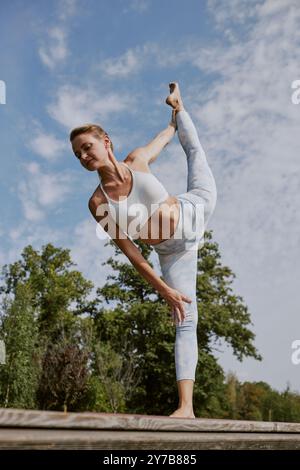Ripresa da un angolo basso di giovane donna caucasica con spaccature in piedi, si è concentrata sull'esercizio fisico Foto Stock
