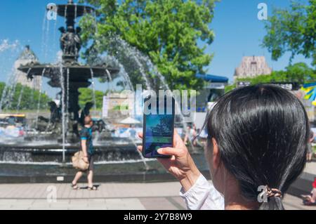 Una donna che scatta foto del monumento, Fontaine de Tourny, fontana della città di Quebec in Canada. Foto Stock