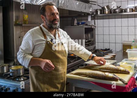 Lo chef René Bobzin prepara il pesce disossato con vari piatti di patate nella cucina del Bauernstube di Bobzin e li presenta personalmente al tavolo della cena. Dewichower Straße, Usedom-Süd, Meclemburgo-Vorpommern, Germania Foto Stock