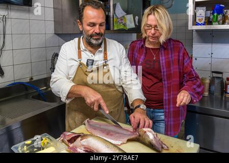 Lo chef René Bobzin prepara il pesce disossato con vari piatti di patate nella cucina del Bauernstube di Bobzin e li presenta personalmente al tavolo della cena. Dewichower Straße, Usedom-Süd, Meclemburgo-Vorpommern, Germania Foto Stock