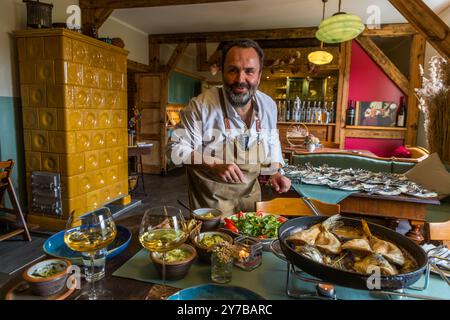 Lo chef René Bobzin prepara il pesce disossato con vari piatti di patate nella cucina del Bauernstube di Bobzin e li presenta personalmente al tavolo della cena. Dewichower Straße, Usedom-Süd, Meclemburgo-Vorpommern, Germania Foto Stock