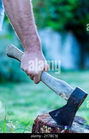 Mani e ascia nella legna da ardere, uomo che trita legna per il fuoco Foto Stock