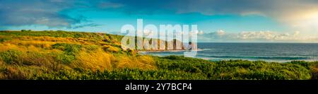 Panorama della spiaggia di Cape Woolamai che mostra la formazione rocciosa dei Pinnacoli al tramonto, Phillip Island, Australia. La luce dorata del sole splende sul Foto Stock