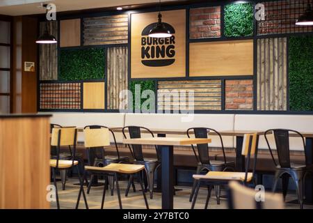 Bielorussia, Minsk - 18 luglio 2024: Un ristorante Burger King che dispone di una disposizione di tavoli e sedie, progettato per il comfort dei clienti durante la cena Foto Stock