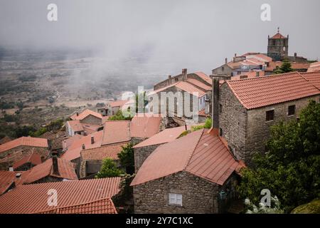 Una vista delle case di Monsanto, Portogallo, mentre la nebbia scende nella valle, creando un'atmosfera serena e mistica sul villaggio. Foto Stock