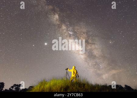 Persona che fotografa il cielo durante la strada tortuosa di notte, vista posteriore di un uomo che scatta una fotografia del cielo notturno Foto Stock