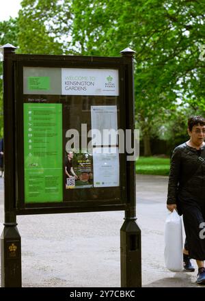 Londra, Inghilterra, aprile 30 2023: Consiglio dei Kensington Gardens con informazioni e una signora di passaggio Foto Stock