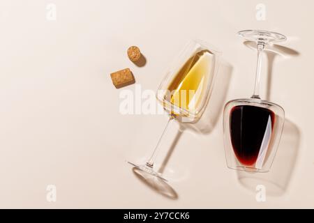 Due bicchieri da vino accanto a diversi tappi di sughero, tutti disposti su uno sfondo luminoso. La luce dura crea ombre nitide, aggiungendo un effetto drammatico alla S. Foto Stock
