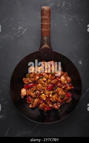 Piatto tradizionale cinese, pollo kung pao in wok pan su sfondo scuro, vista dall'alto Foto Stock
