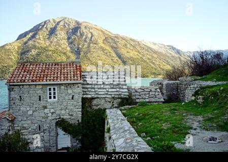 Chiesa di nostra Signora degli Angeli ('Gospa od Anđela') nella baia di Cattaro con una montagna sullo sfondo. Chiesa fortificata nello stretto di Verige Foto Stock