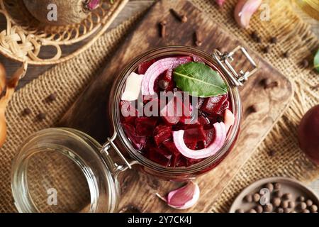 Preparazione di barbabietole fermentate in un vaso di vetro a base di barbabietole fresche, cipolle, aglio e spezie, vista dall'alto Foto Stock