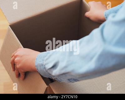 Una persona che apre una scatola di cartone. Profondità di campo ridotta. Primo piano. Foto Stock
