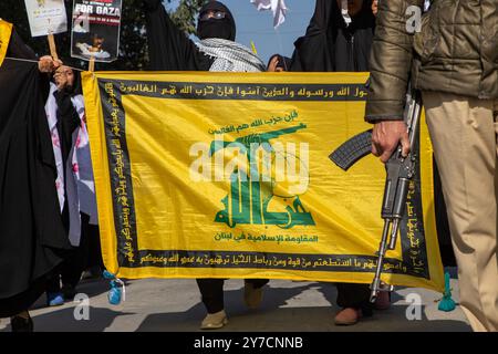 Il poliziotto indiano è in guardia mentre i musulmani del Kashmir tengono uno striscione di Hezbollah durante una protesta contro l'uccisione del defunto capo di Hezbollah, Hassan Nasrallah. Migliaia di manifestanti sono scesi in strada a Srinagar e attraverso il Kashmir per piangere e condannare l'uccisione del capo Hezbollah, Hassan Nasrallah, e di altri comandanti di alto livello in un attacco aereo israeliano. Hezbollah ha confermato la morte del suo leader, Hassan Nasrallah, sabato dopo che le forze di difesa israeliane hanno colpito quello che ha chiamato il "quartier generale centrale" di Hezbollah con un massiccio sciopero venerdì 27 settembre 2024, che ha livellato diversi residenti Foto Stock