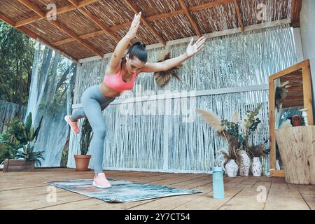 Bella giovane donna in abbigliamento sportivo che si esercita sul patio Foto Stock