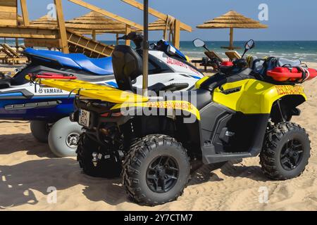 Altura, Portogallo, 24 settembre 2024. Veicoli di soccorso e attrezzature di bagnino posizionati vicino a una torre di bagnino su una spiaggia soleggiata. Foto Stock