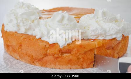 Lo chef taglia la torta. Torta di frutta appena sfornata con panna montata e primo piano Foto Stock