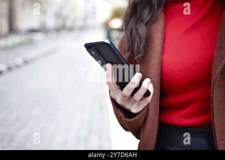 Telefono cellulare in mano a una donna. Cellulare in mano. Usando il cellulare per strada Foto Stock