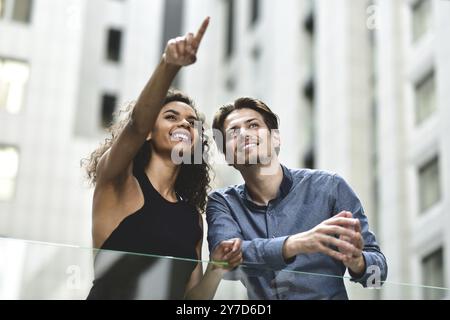 Una felice coppia internazionale ha una conversazione in città. Donna di razza mista e uomo caucasico Foto Stock