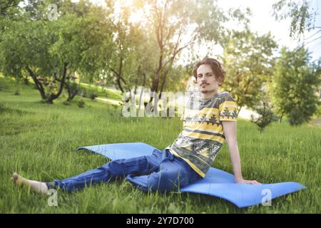 Un bell'elegante ragazzo ama la natura e sogna qualcosa seduto nel parco. vista tranquilla. atmosfera estiva Foto Stock