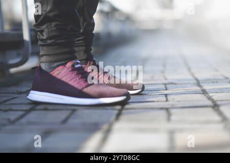 Un uomo in sneakers cammina per strada in una giornata di sole Foto Stock