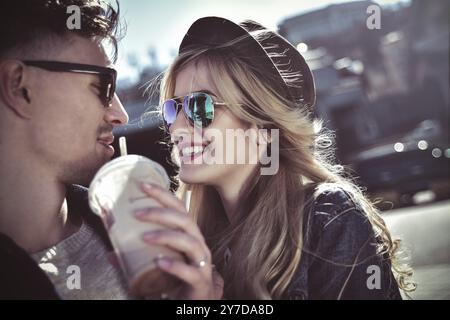 Una coppia sorridente cammina per strada nel fine settimana e bevi qualche cocktail Foto Stock