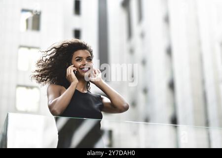 Felice sorridente donna afroamericana fare una bella conversazione in strada Foto Stock