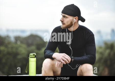 Muscolare atleta barbuto controllo calorie bruciate su smart guarda dopo una buona sessione di allenamento sulla città Foto Stock