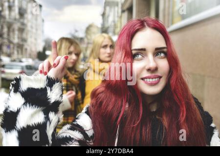 La ragazza teenage sicura di sé ignora le persone gelose che diffondono pettegolezzi dietro di lei. Stop bullismo. Problemi sociali. Una ragazza mostra il suo dito medio t Foto Stock