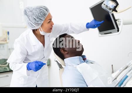 Dentista donna che indica il display per mostrare le informazioni al paziente Foto Stock